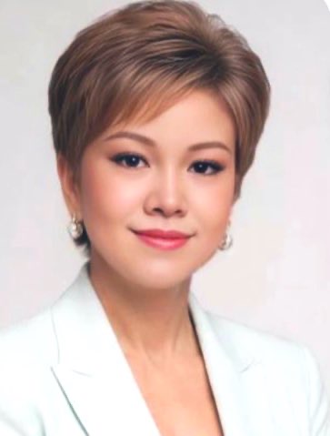 短髮棕金色女性微笑,穿白色外套,淡妝精緻,背景為淺色純淨。